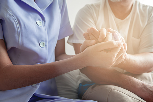 Close up of a nurse holding the hand of an elderly person